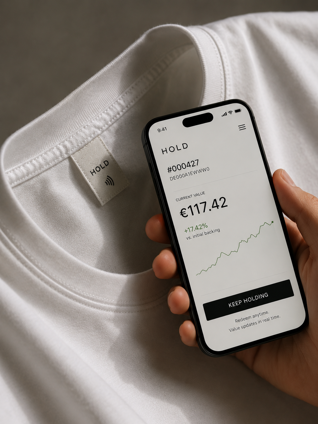 A phone held above a HOLD NFC garment label showing a digital profile